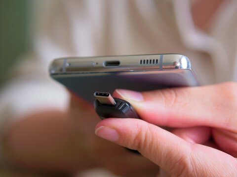 Close-up of hands plugging a USB-C flash drive adapter into a modern smartphone