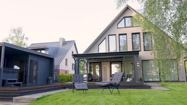 Modern Scandinavian house exterior with large windows, green lawn, and outdoor seating area showcasing contemporary architecture design