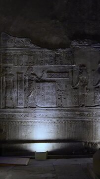 Dendera temple interior sanctuary with illuminated hieroglyphic walls and ritual reliefs in Egypt, ancient sacred chamber with dramatic lighting on carved sandstone surfaces.