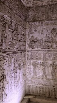 Dendera temple interior sanctuary with illuminated hieroglyphic walls and ritual reliefs in Egypt, ancient sacred chamber with dramatic lighting on carved sandstone surfaces.