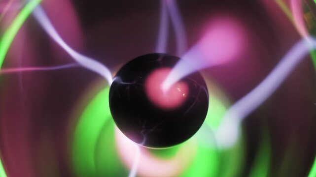 Macro view of a plasma ball central electrode emitting pink and purple electric bolts. Wavy ionized gas filaments and streamers glow with green light on a dark background.