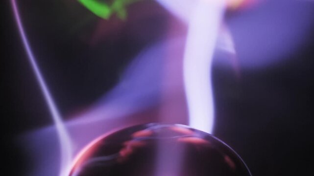 Macro view of an intense plasma lamp central electrode emitting bright blue and pink electric bolts. Ionized gas arcs move inside the glass dome on a dark background.
