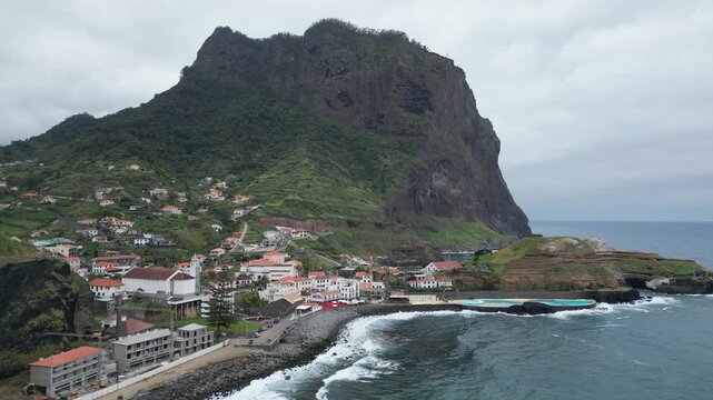 Drone flying backward revealing Penha dAguia mountain and Porto da Cruz