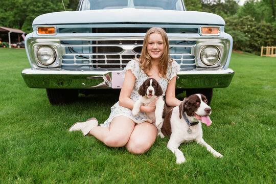 young woman sitting in front of truck with dogs