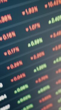 Digital screen shows fluctuating stock market prices with red and green percentage changes. A shallow depth of field focuses on the pixelated numbers as the financial data updates.