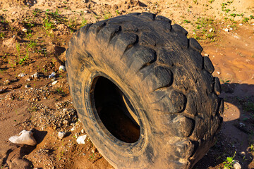 Huge worn-out mining dump truck tire abandoned in a dusty quarry, highlighting serious environmental pollution and industrial waste management issues in a desolate landscape © PhotoChur