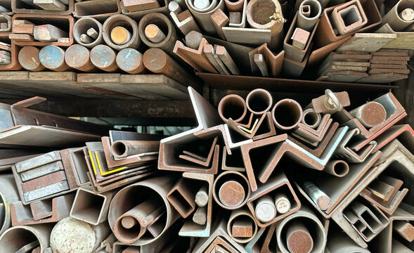 Diverse collection of metal profiles, pipes stacked in workshop