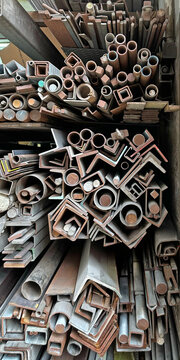 Diverse collection of metal profiles and pipes stacked in a workshop