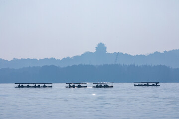 Misty lake with boats and distant pagoda silhouette in Hangzhou, China © NgoLanThu