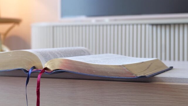 Open holy bible with gold pages on modern wooden table