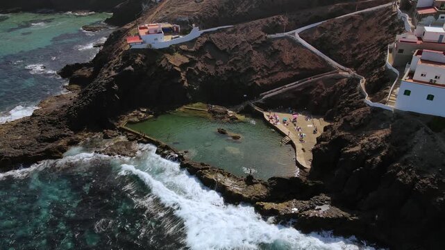 Aerial view of the natural swimming pool of El Clavo, or La Furnia, on the coast of Galdar. People enjoying a sunny day at this tourist spot