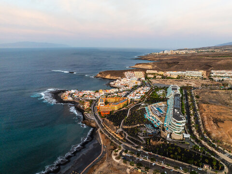 Aerial view of the coastline featuring modern resorts, volcanic terrain, and the Atlantic Ocean in Costa Adeje, Canary Islands, Spain.