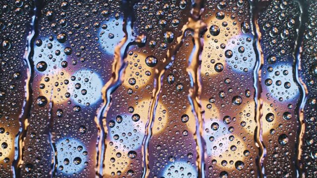 Abstract background of colorful water droplets and streaks on a glass surface with blurred bokeh lights in blue and gold tones Keywords: water, droplets, streaks, glass, surface, abstract