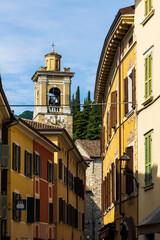 Fototapeta premium Bell tower of the Chiesa di San Francesco framed by an alleyway in the historic center of Gargnano, Lombardy