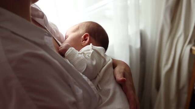 young mother breastfeeds a newborn at home