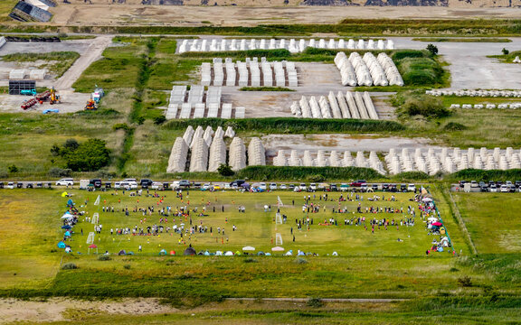 Aerial view of Kenmin Seaside Park featuring a soccer field with people playing, parked cars, and rows of concrete blocks in the background in Kanazawa, Ishikawa, Japan.