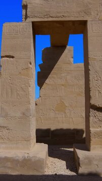 Seti I mortuary temple exterior with Osiride colonnade and palm trees in Luxor Egypt. Ancient sandstone ruins in desert landscape.