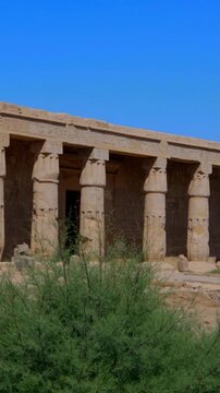 Seti I mortuary temple entrance with palm tree alley and ancient stone ruins in Luxor Egypt. Scenic pathway under vivid blue sky.