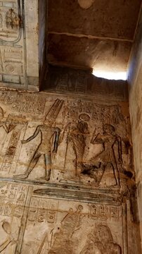 Ancient painted walls and ceiling with gods figures, hieroglyphics and cartouches inside Seti I temple, Luxor Egypt.