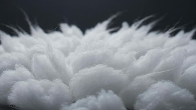 Macro shot of white synthetic polyester fiber filler for toys and pillows, showcasing the soft texture of the insulating and stuffing material against a dark background