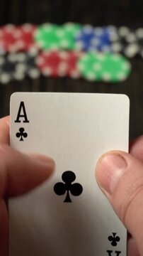Player reveals three aces, one red heart and one black spade, while colorful poker chips are scattered on a wooden table in the background