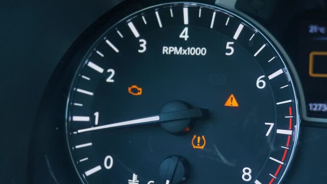 Car dashboard displaying check engine and low tire pressure warning lights