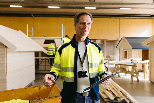 Male educational professional holding notepad giving instructions in construction and civil engineering class at high sc