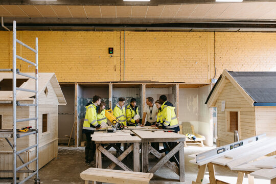 Construction training workshop of students being held in workshop surrounded by small wooden sheds at vocational high sc