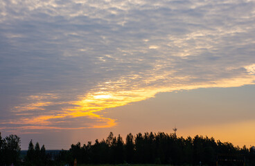Fototapeta premium Dramatic sunset clouds over rural tree line