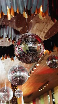 Vertical video. Hanging mirror disco balls decorating wedding reception tent ceiling.