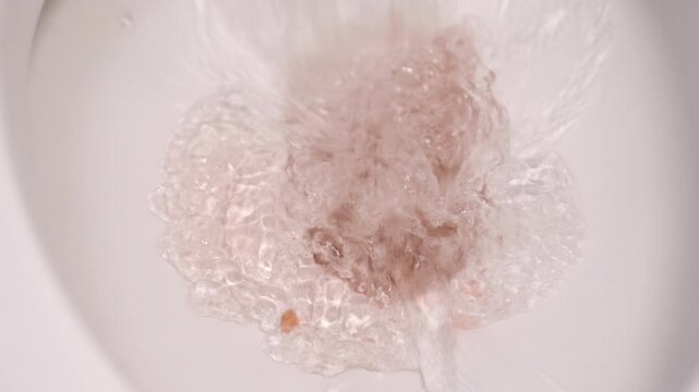 Flushing away drops of blood into the toilet bowl signifies illness or injury in the digestive tract, such as passing blood in the stool or hemorrhoids.