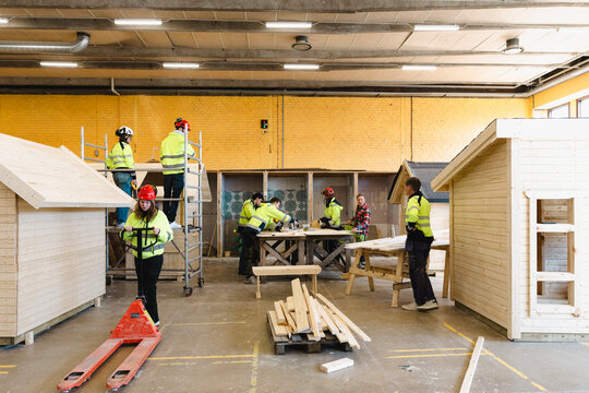 Teachers guiding students in doing carpentry tasks at vocation school workshop