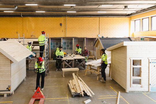 High angle view of teachers guiding students in doing carpentry tasks at vocation school workshop
