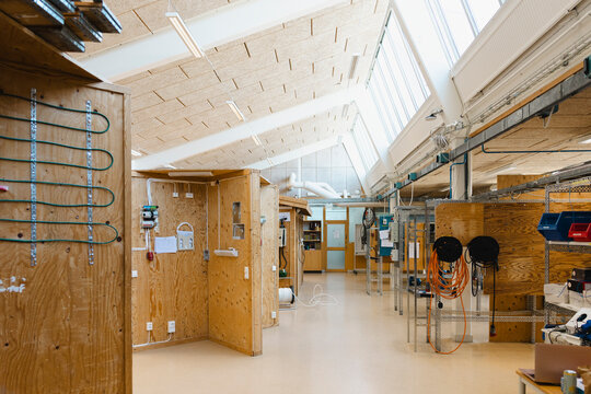Wooden practice stalls and shelving units in spacious electrical training facility at secondary school