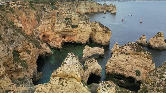 Close drone view of vertical limestone cliffs at Ponta da Piedade, with Atlantic waves, natural caves and textured rock layers shaped by the ocean