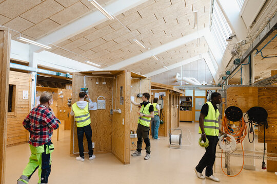 Professor observing students working on electric circuits in civil engineering workshop at vocational school