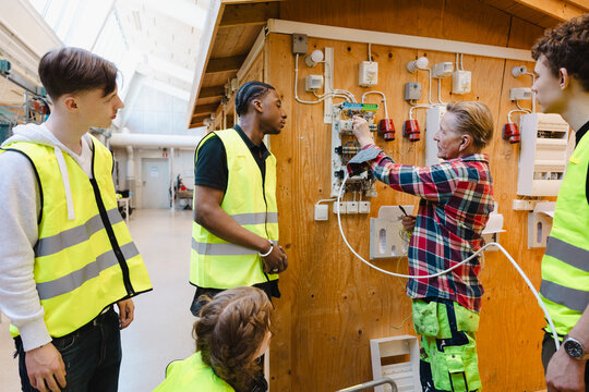 Senior male engineer teaching students about wiring of electric circuit in training session at vocational workshop