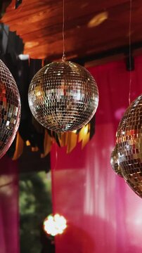 Vertical video. Decorative mirror disco balls suspended inside wedding reception hall.