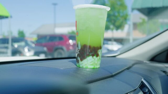 Iced green bubble tea with boba pearls on car dashboard