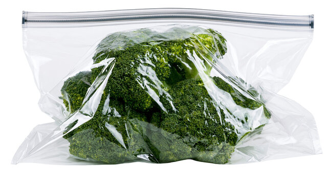 Fresh green broccoli florets sealed in a clear plastic zipper bag, isolated on transparent background