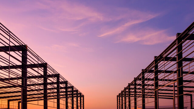 Silhouette 2 modern industrial steel framework buildings structure under twilight sky, factory construction background in symmetric low angle view with copy space