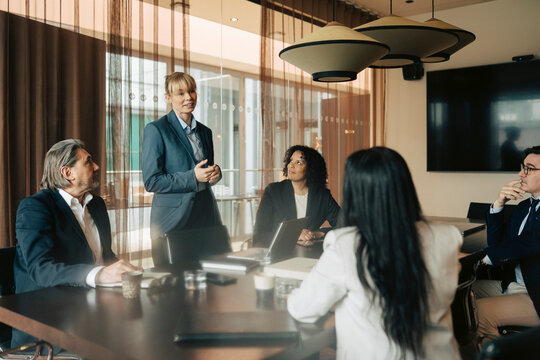Female business executive pitching sales strategies to corporate partners during meeting in office