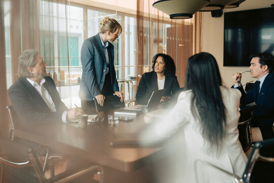 Businesswoman raising questions on proposed sales strategy by female expert during meeting in office