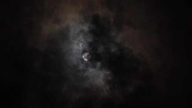 Clouds illuminated by full moon against night sky