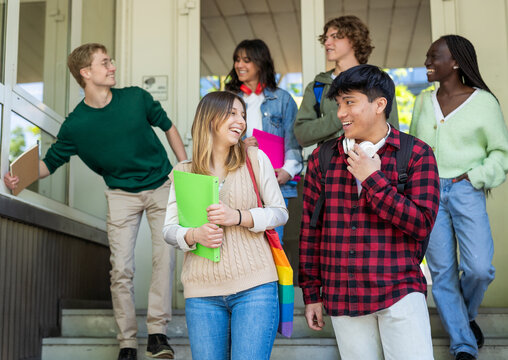 Multiethnic Group of Young Students Laughing While Exiting School Together