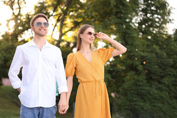 Fototapeta premium Lovely couple in sunglasses outdoors on sunny day, space for text