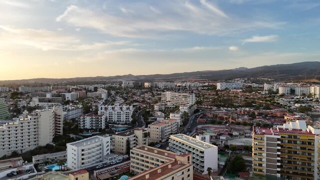 Aerial panorama flight over hotels in Playa del Ingles towards mountains in the evening on Canary Island Gran Canaria, Spain