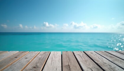 Fototapeta premium Wooden pier overlooks bright blue ocean water under clear sky. Gentle waves reflect sunlight. Calm seaside expanse invites peaceful contemplation and relaxation.
