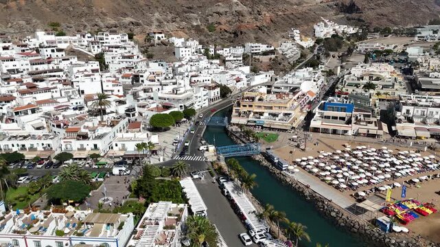 Aerial panorama flight towards Puerto de Mogan with beach, white houses and canal on Canary Island Gran Canaria, Spain