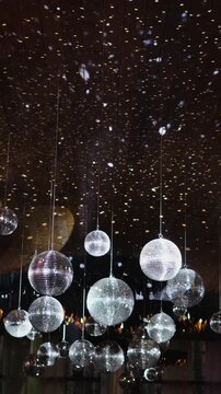 Vertical video. Mirrored disco balls hanging as wedding decor above the reception dance floor.